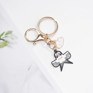 Détail des pendentifs hirondelle et nuage en métal doré avec double anneau de clé