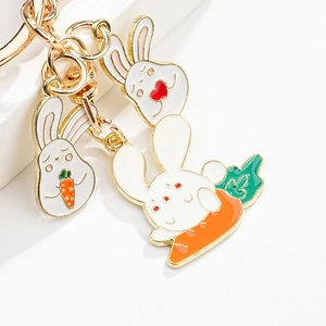 Detailed macro view of cute cartoon white enamel bunny keychains with gold metal finish