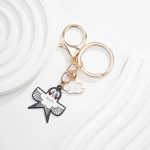 Détail des breloques hirondelle de dessin animé et nuage blanc sur un porte-clés doré