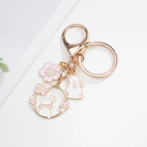 Detail of pink enamel cherry blossom and white rabbit metal keychain with golden lobster clasp