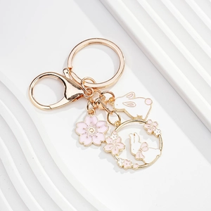 Detailed close-up of a golden cherry blossom rabbit keychain with pink enamel charms