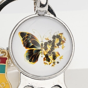 Macro view of vintage metal keychain showing colorful butterfly and floral art glass gem