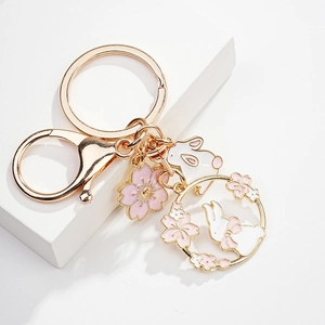 Detail of pink cherry blossom and white rabbit metal keychain on white pedestal