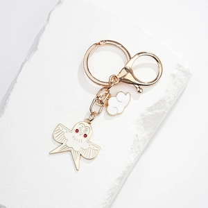 Détail d'un porte-clés oiseau doré avec émail blanc et petits strass rouges brillants