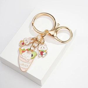 Detailed view of golden keychain with enamel bunny and strawberry cat charms on white stand