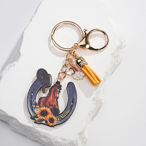 Detail of horseshoe keychain with sunflower motif, leather tassel, and rainbow charm