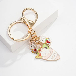 Detail of golden keychain with enamel pendants featuring a cute rabbit and cat in a crepe