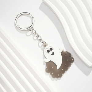 Close-up of a cute cartoon ghost keychain with a grey base and silver metal keyring