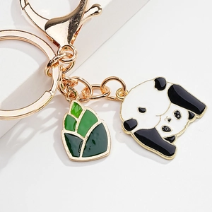 Close-up of golden metal panda keychain with green bamboo shoots on white background