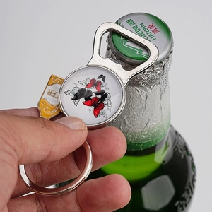 Action shot of vintage butterfly metal bottle opener keychain opening a glass beer bottle