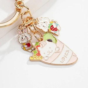 Close-up of golden keychain with enamel cat crepe, strawberry cat, and apron bunny charms