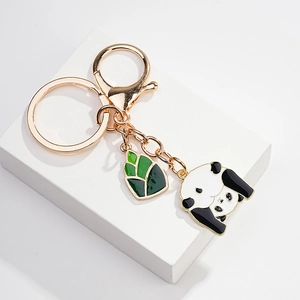 Close-up of golden keychain with enamel panda charm and green bamboo shoot pendant