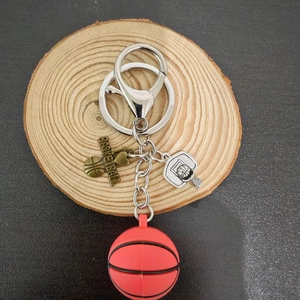 Portachiavi basket 3D con palla rossa e canestro argentato su un disco di legno rustico