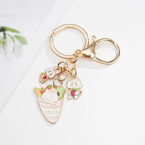 Detail of golden alloy keychain with cute rabbit and cat charms on a white background