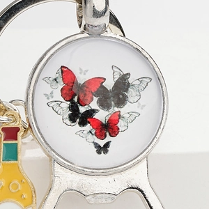 Vintage metal keychain with red butterfly gem and colorful bottle charm on white background