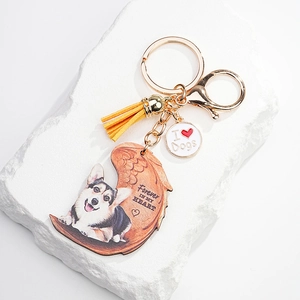 Detail of wooden angel wing keychain with Corgi print, golden lobster clasp and yellow tassel