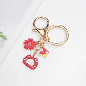 Detail view of rabbit and cherry blossom enamel charms on a gold keychain clasp