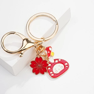 Detail of red cherry blossom and mushroom charms on a gold plated keychain