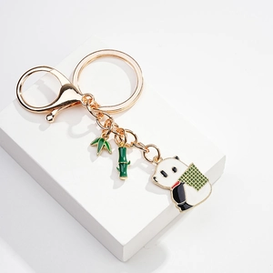 Detail showing cartoon panda and green bamboo enamel charms on a golden metal keychain