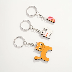 Close-up of three cute cartoon wooden cat keychains with metal rings on white background