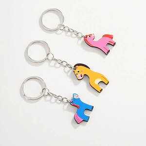 Close-up of three cute wooden pony keychains in pink, yellow, and blue colors