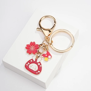 Detailed macro view of cute red rabbit and mushroom enamel charms on a gold keychain