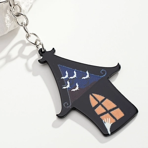 Detail of Halloween haunted house keychain with blue sky, white bats and orange windows