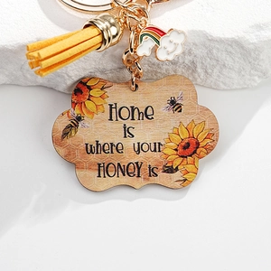 Macro detail of sunflower bee keychain with wooden charm and yellow leather tassel