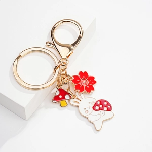 Close-up of golden keychain with cute white rabbit, mushroom and cherry blossom charms