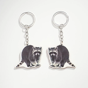 Close-up of two realistic wooden raccoon keychains with silver metal rings and chains