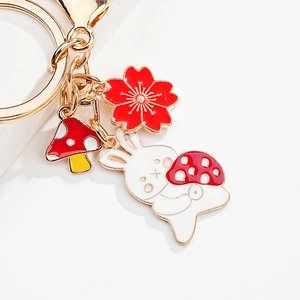 Close-up of a metal rabbit keychain with red mushroom and cherry blossom charms