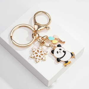 Detail of golden metal keychain featuring skating panda, white snowflake and colorful balloons