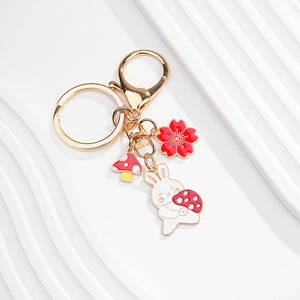 Detail view of rabbit and cherry blossom enamel charms on a gold metal keychain