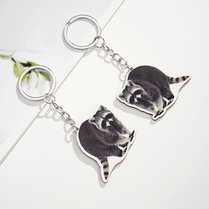 Macro view of two realistic wooden raccoon keychains with silver metal rings and chains