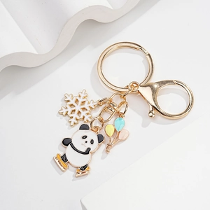 Close-up of golden panda skating keychain with white snowflake and balloon charms