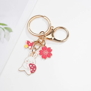 Detail of bunny keychain with cherry blossom and mushroom charms on gold ring
