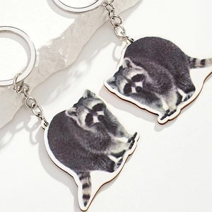 Creative realistic raccoon wood keychain set with silver metal rings on a stone surface