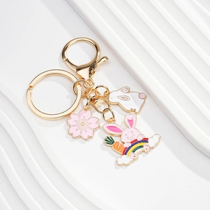 Close-up of golden rabbit keychain with pink cherry blossom and rainbow cloud charms