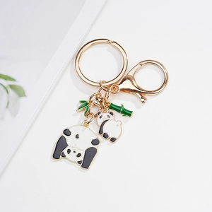 Detailed close-up of golden metal panda keychain with enamel charms and bamboo leaf charm