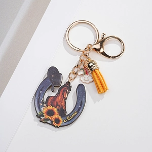 Close-up of horseshoe keychain with sunflower design, yellow tassel and rainbow charm
