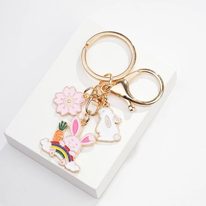 Detail of pink cherry blossom and white rabbit enamel pendants on a gold keychain