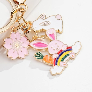 Close-up of pink cherry blossom and cute bunny charms on a gold metal keychain
