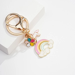 Detail of gold keychain with colorful enamel flower, white unicorn, and rainbow charms