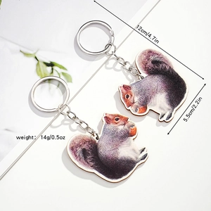 Set of two realistic wooden squirrel keychains with silver rings on marble surface