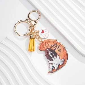 Close-up of dog memorial keychain with yellow tassel and wing shaped acrylic pendant