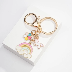Detailed macro view of rainbow, unicorn, and flower enamel charms on a gold keychain