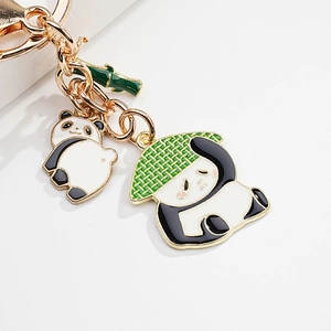 Detail of golden panda keychain featuring enamel bamboo hat panda and bamboo charm