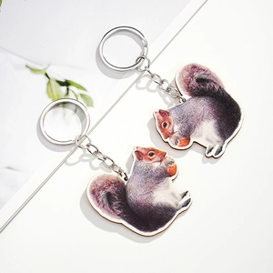 Close-up of two realistic squirrel wooden keychains with silver metal rings on white