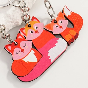 Cute cartoon fox wooden keychains with silver rings on a light grey textured background