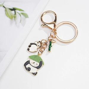 Detail of cartoon panda charms and green bamboo pendant on a gold metal keychain